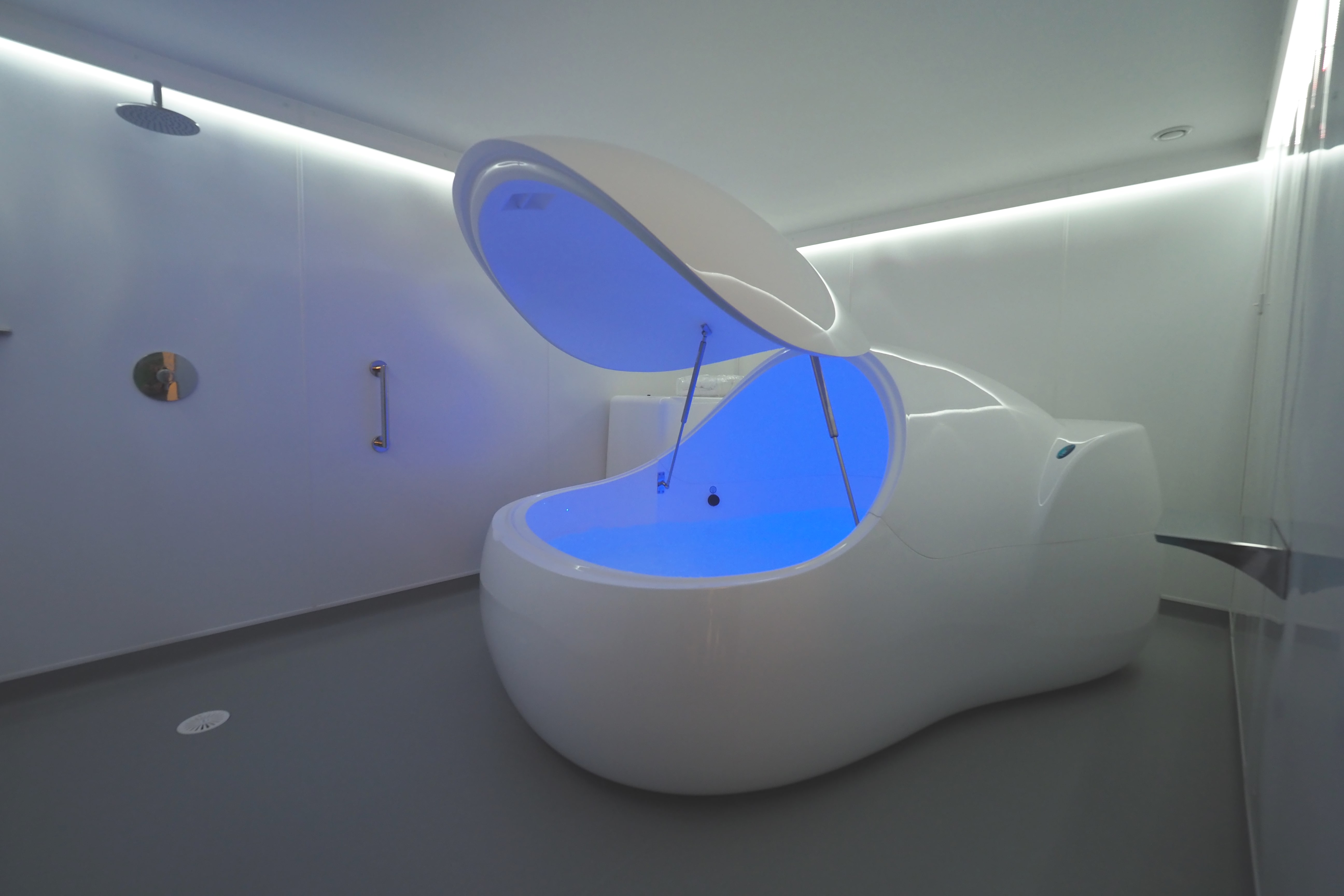 A state of the art floatation pod gleaming clean and white in a bright luxurious room